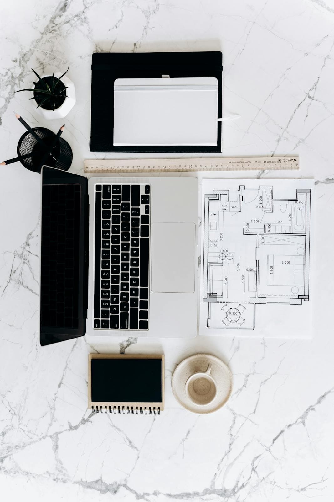 Bureau lumineux avec laptop ouvert et documents parfaitement alignés sur une table en marbre